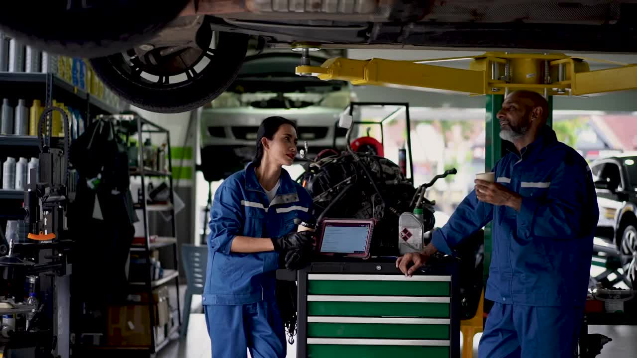 亚洲资深男机械师和一位年轻的女同事使用技术诊断和解决机械问题视频下载