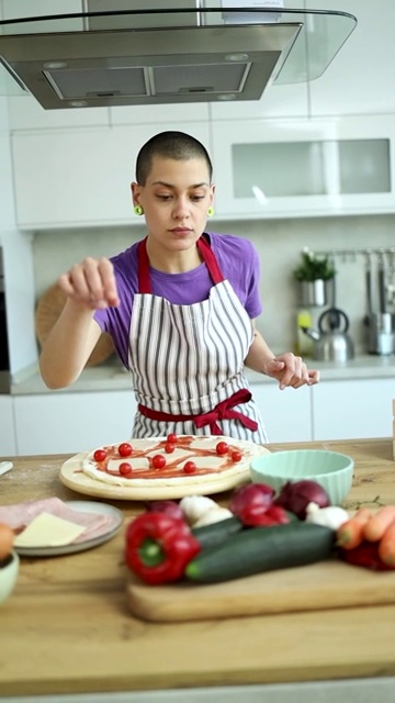 快乐的短发女孩在围裙享受烹饪披萨在家庭厨房视频下载