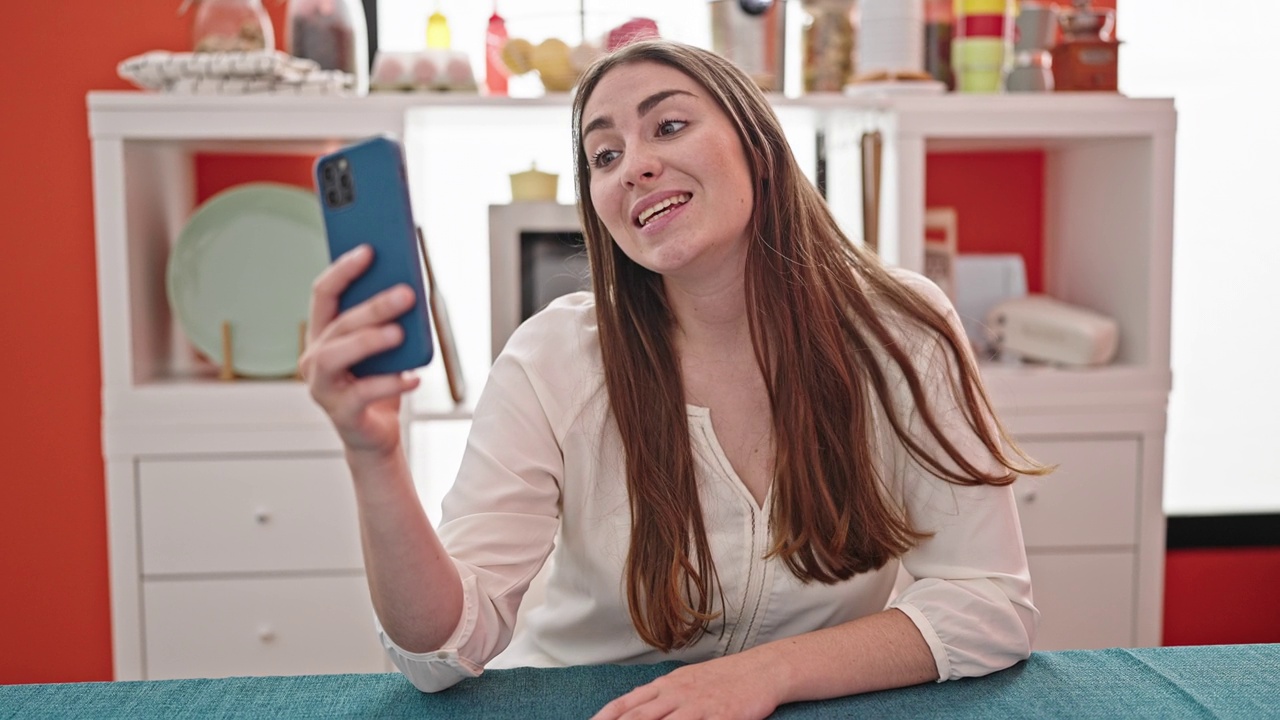 年轻美丽的西班牙女子正在视频通话坐在餐桌上的餐厅视频素材