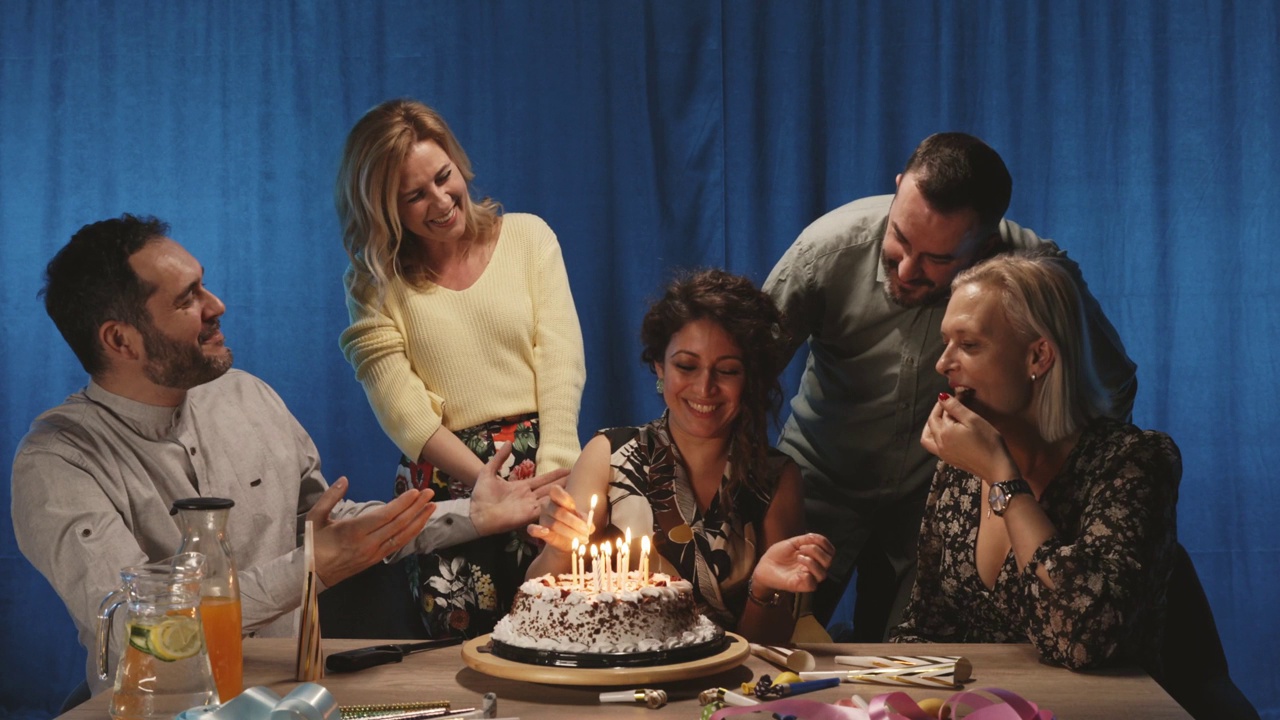 一群朋友点燃蛋糕上的蜡烛，唱生日歌视频素材