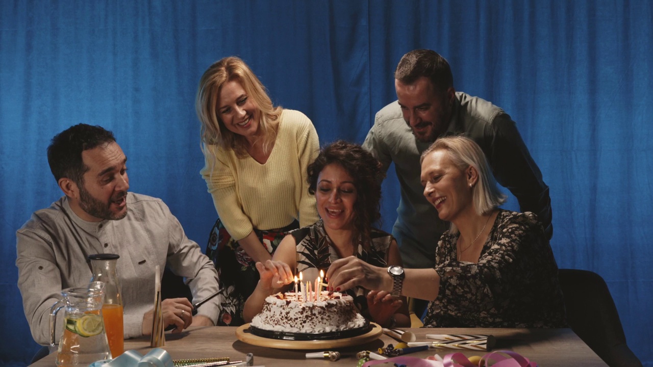 一群朋友点燃蛋糕上的蜡烛，唱生日歌视频素材