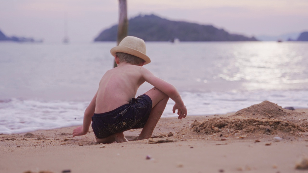 小男孩在海边挖沙视频素材