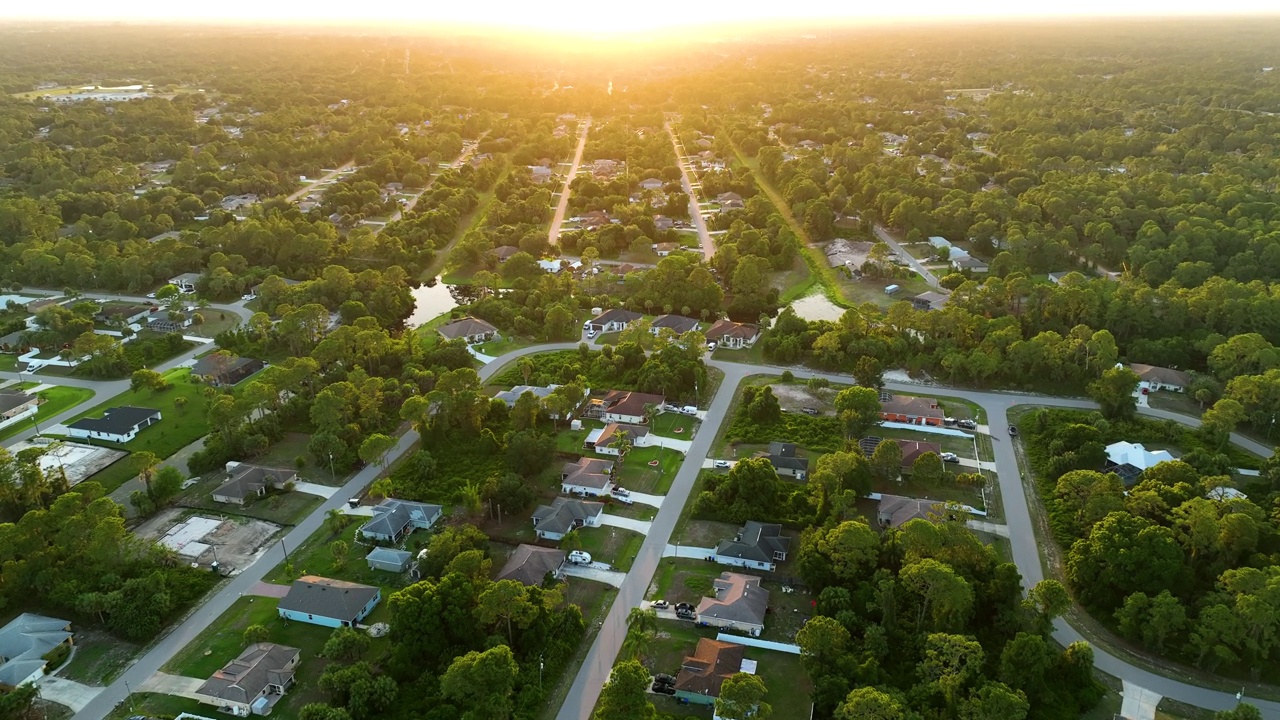 夕阳下，佛罗里达州宁静的乡村地区，在绿色棕榈树之间的郊区私人住宅的鸟瞰图视频素材