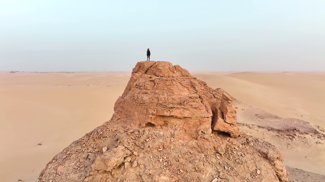 在埃及，一个孤独的旅行者站在一座被金色沙丘环绕的沙漠之巅。视频下载