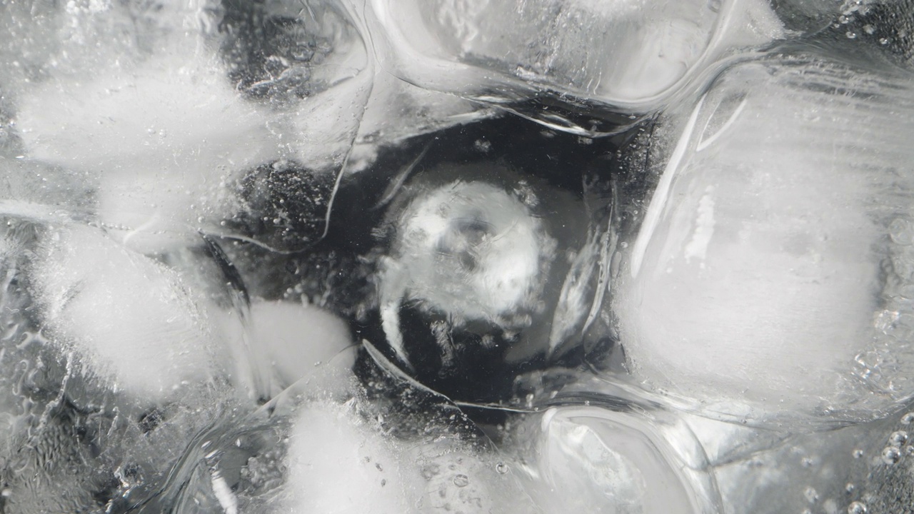 相机被放入一个装有苏打水和冰块的玻璃杯中，里面有气泡。Macro-slider。视频下载