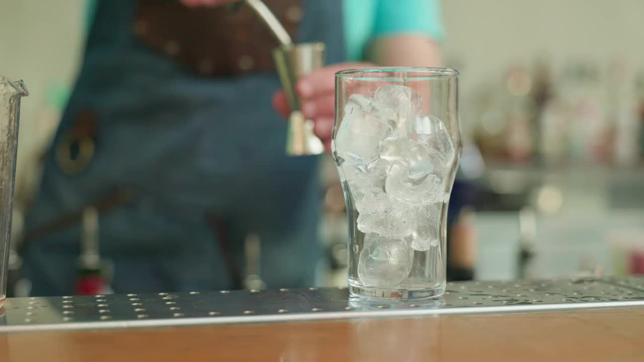 在酒吧里，一位专业的调酒师为顾客准备了一杯加冰块的酒精鸡尾酒视频下载
