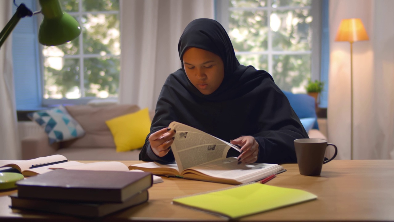 一名穆斯林女学生正在图书馆的书桌前看书。实时视频下载