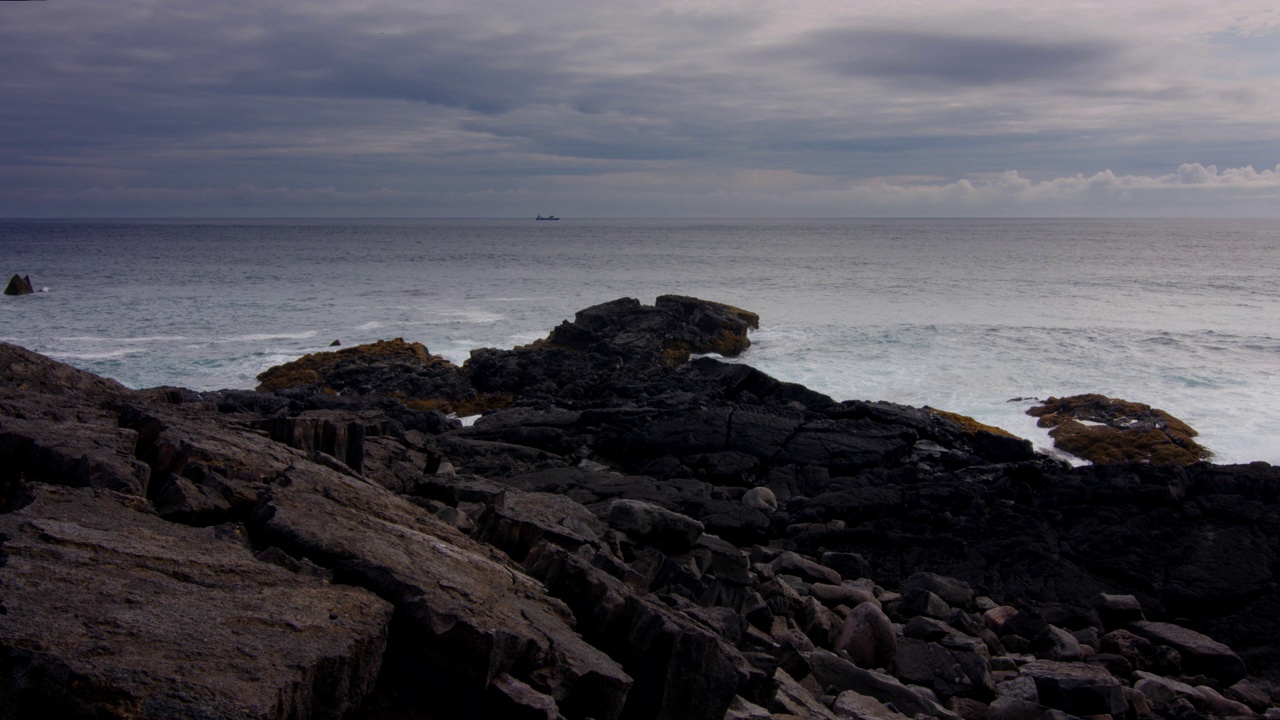 冰岛HDR，在乌云密布的岩石海岸线附近的拖网渔船视频下载