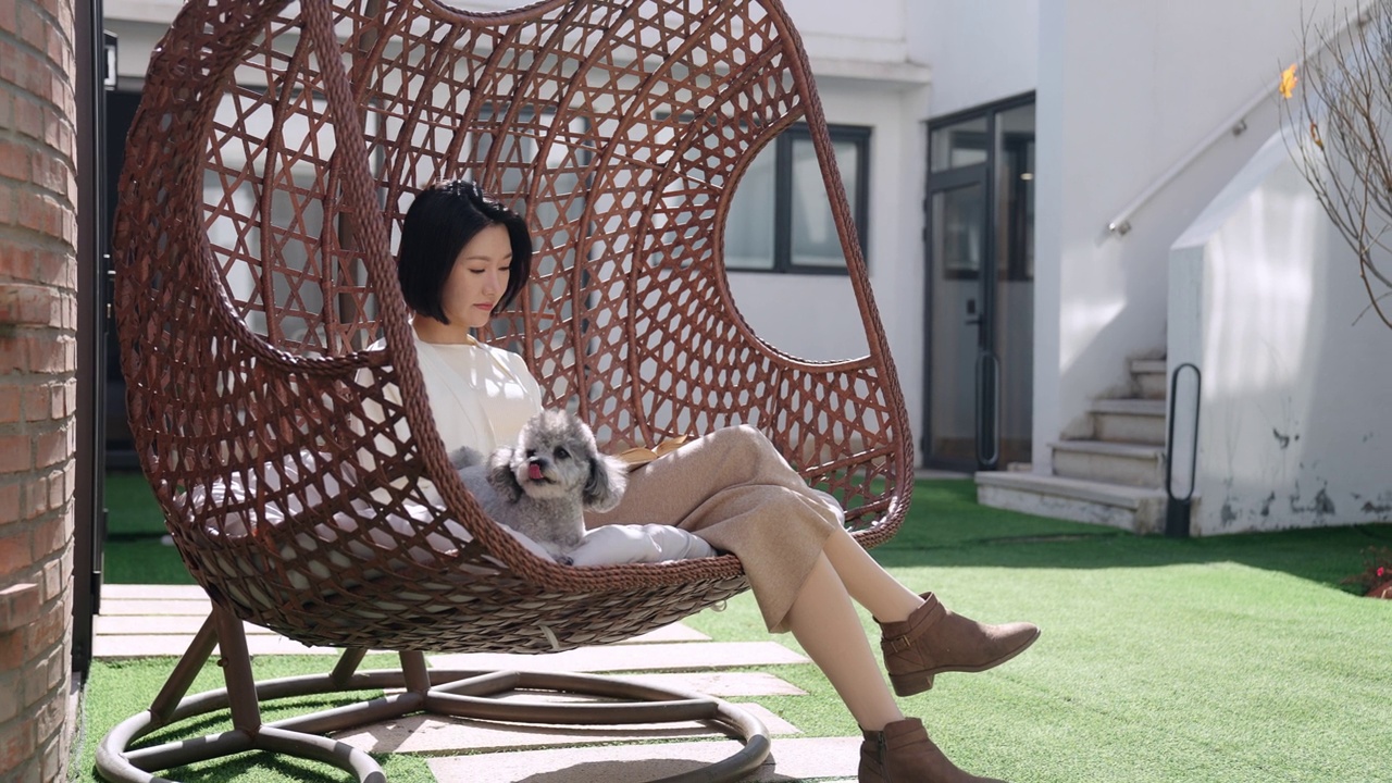 快乐的年轻女子带着宠物狗坐在吊椅上，4K视频下载