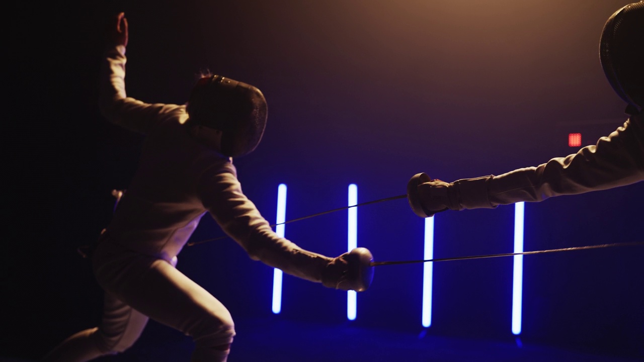 两名职业击剑手在灯光明亮的舞台上格斗。向前猛冲，躲闪视频下载