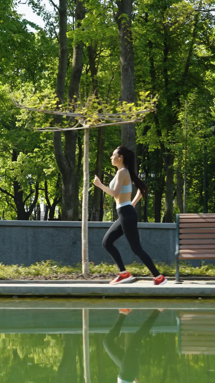 竖屏:适合女性在公园池塘边慢跑视频下载