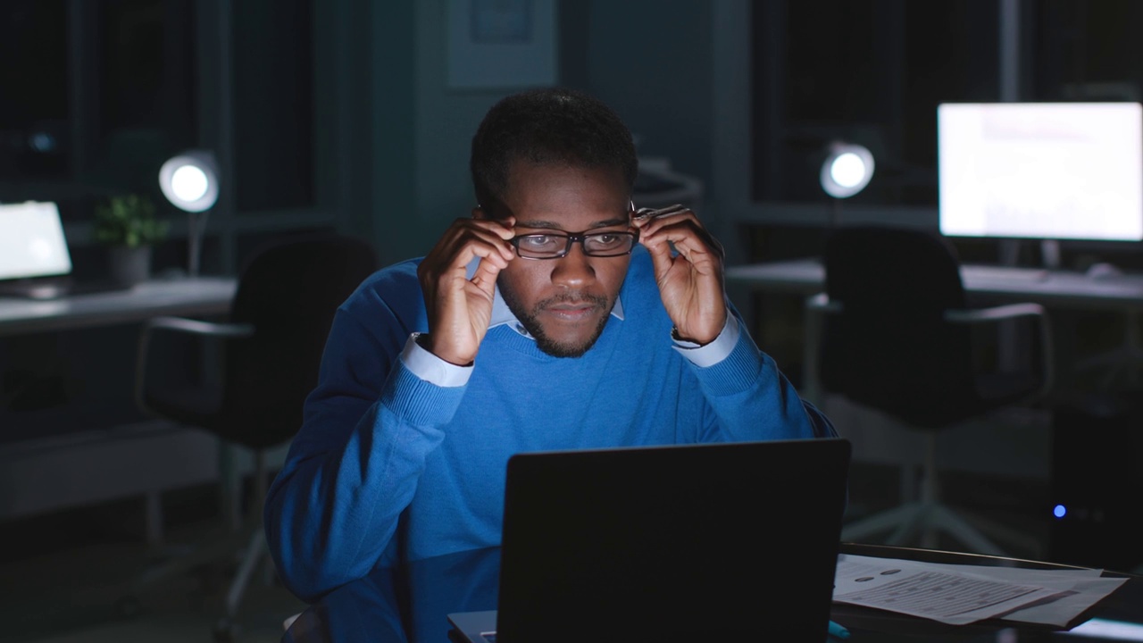 戴眼镜的非裔美国经理在深夜用笔记本电脑看电子邮件视频下载