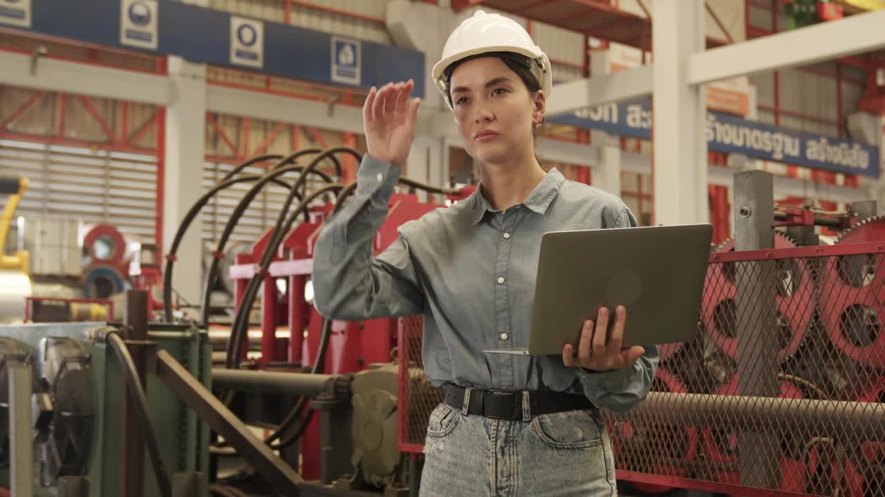 戴着安全帽的女工在大型工厂检查机器。视频下载