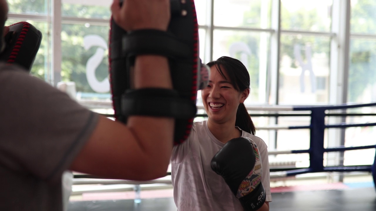 年轻的亚洲女子在拳击馆与男教练一起训练视频下载