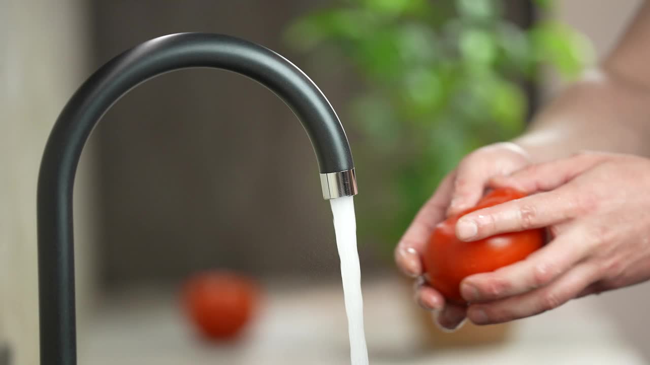用手在水龙头下清洗西红柿。视频素材