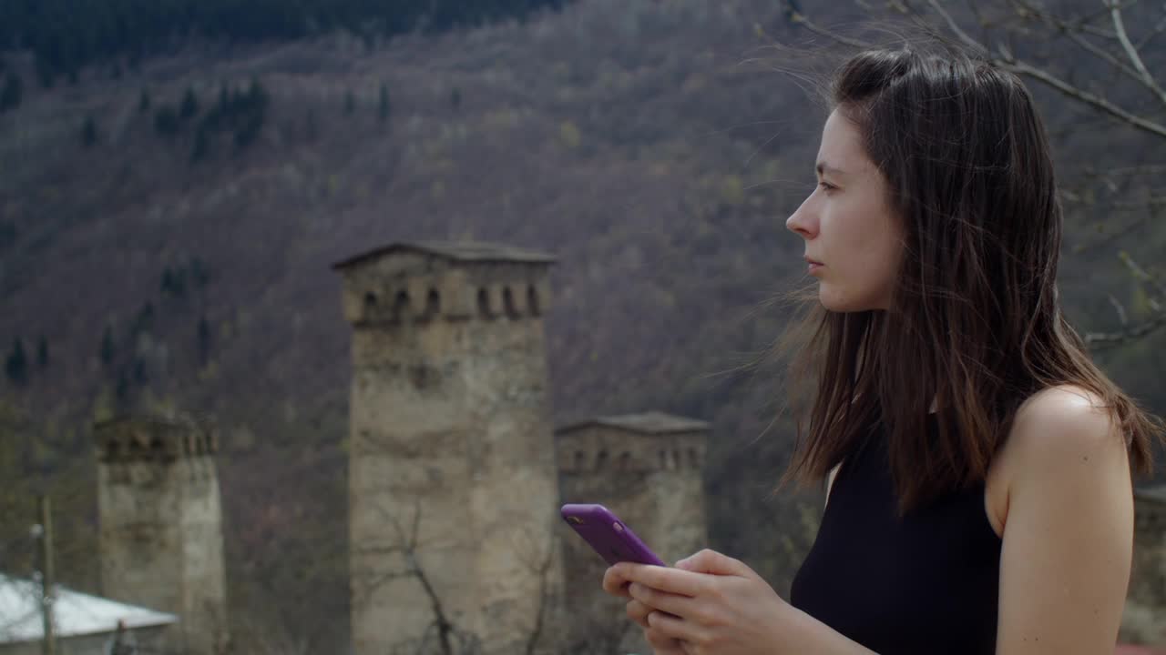 年轻女子在山上拍摄古老的石塔。斯瓦涅季传统的古格鲁吉亚建筑景观。文化遗产视频下载