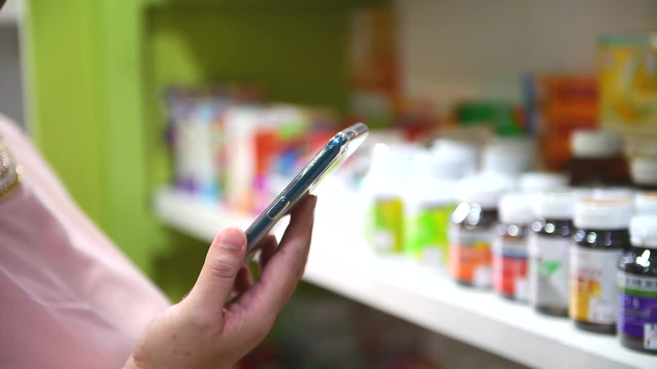 消费者在药店选购商品时通过手机查看信息视频下载