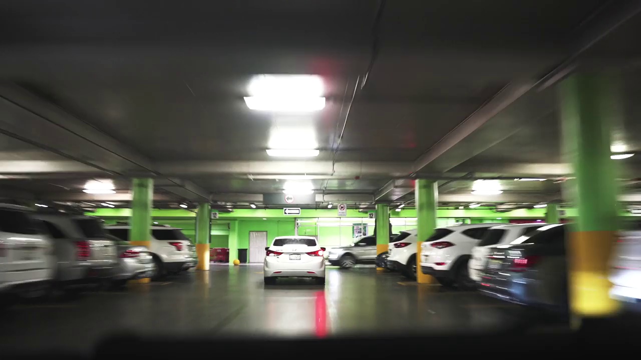 一辆汽车在地下停车场周围行驶，寻找空闲空间，透过挡风玻璃拍摄的延时视图。模糊快速运动视频4K视频下载