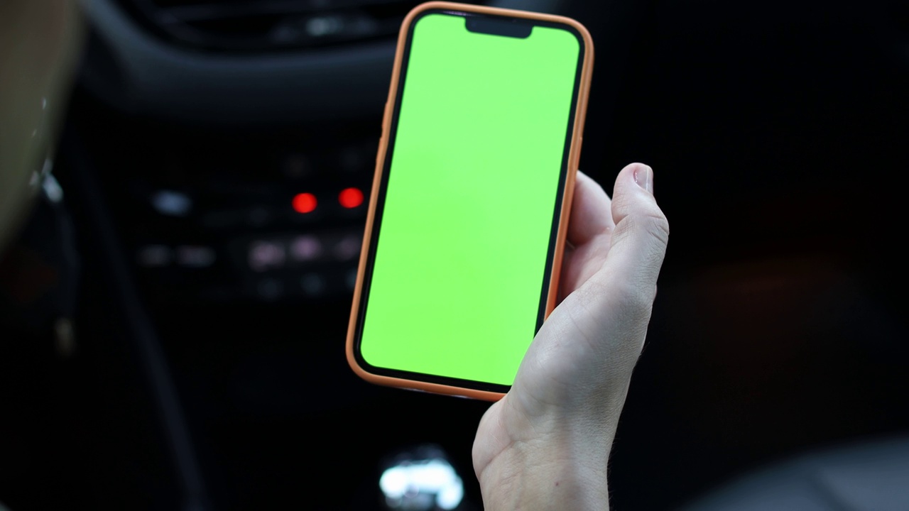 一名女子在车内使用绿屏智能手机视频下载