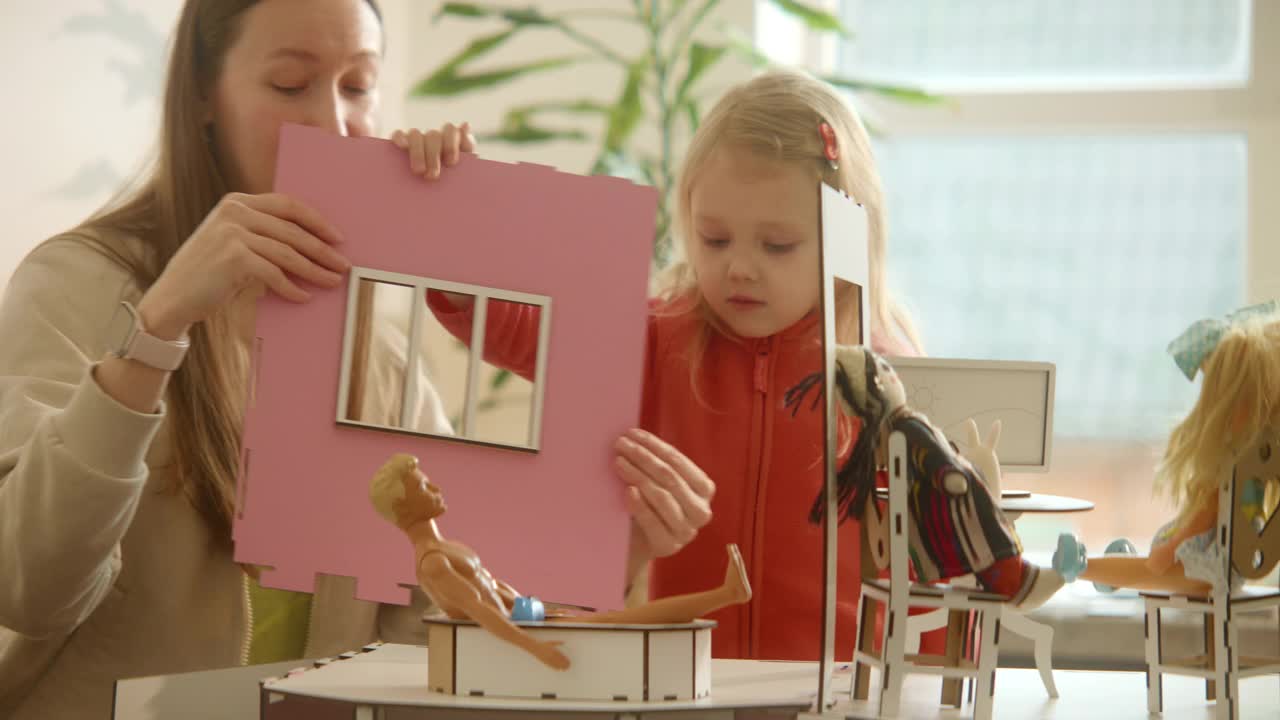 母女俩在组装过程中的木制娃娃屋，粉色时尚娃娃屋视频下载