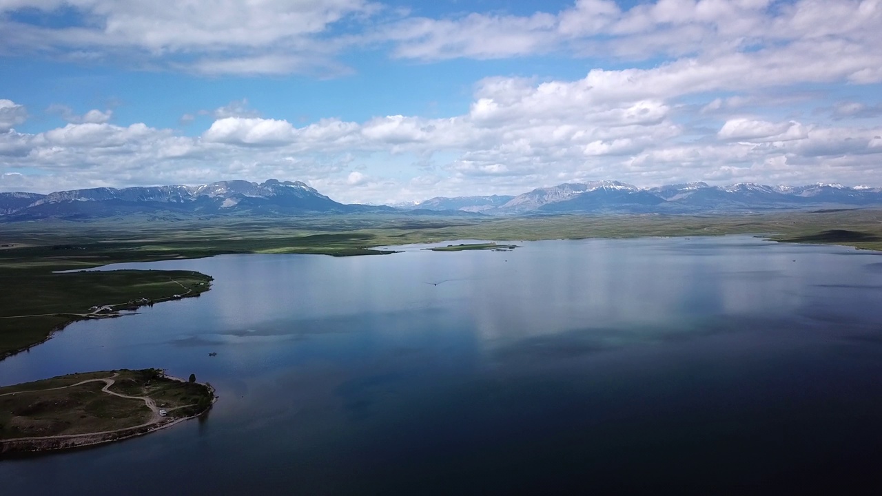 空中拍摄的湖与船在山脉附近的天空，无人机在自然景观上向后飞行-比林斯，蒙大拿视频素材