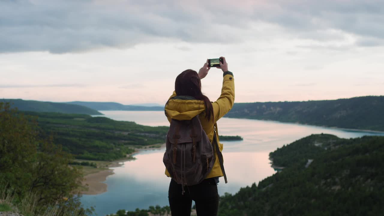 女士用智能手机拍照，分享风景自然背景的照片，享受假期假期旅行冒险视频下载