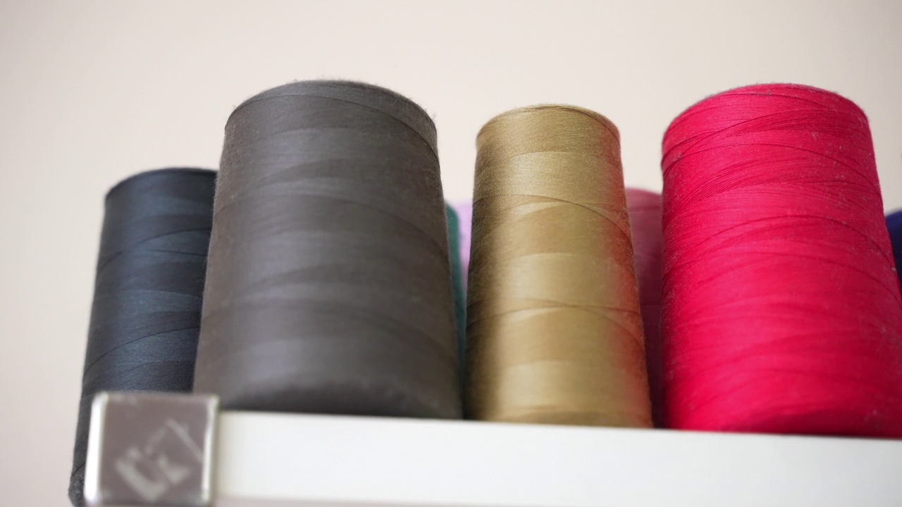裁缝车间货架上的一排排彩色棉线线轴，专业缝纫机的线卷，纺织工业的织物线，缝纫工具，材料和设备的概念视频素材