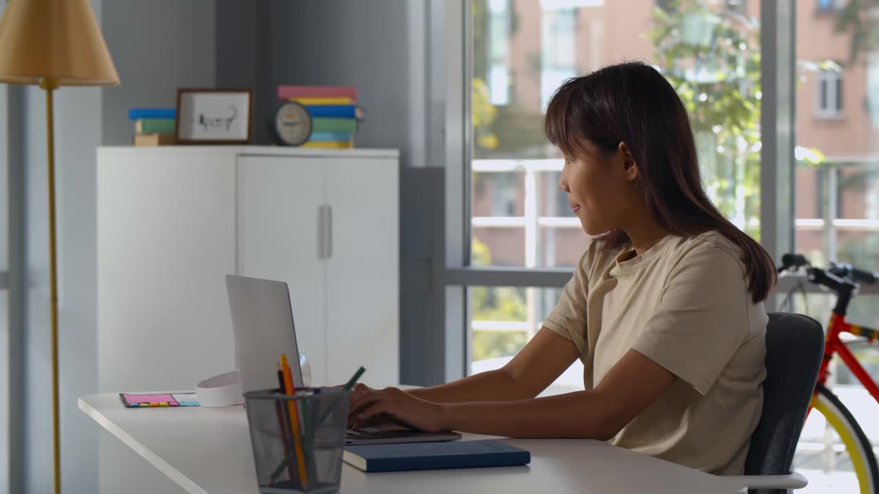 亚洲女学生在笔记本电脑上远程学习的侧视图视频下载
