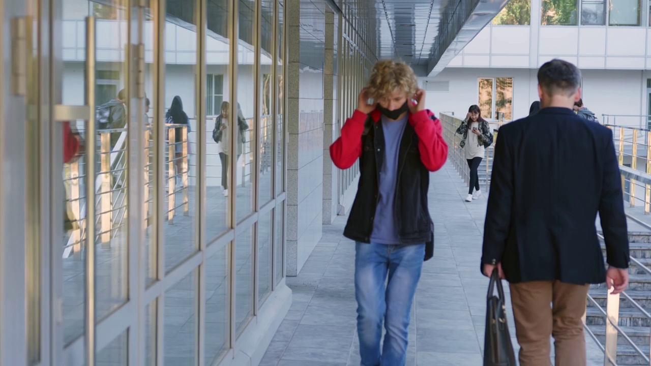 十几岁的男孩戴上安全口罩在学校大楼里行走视频下载