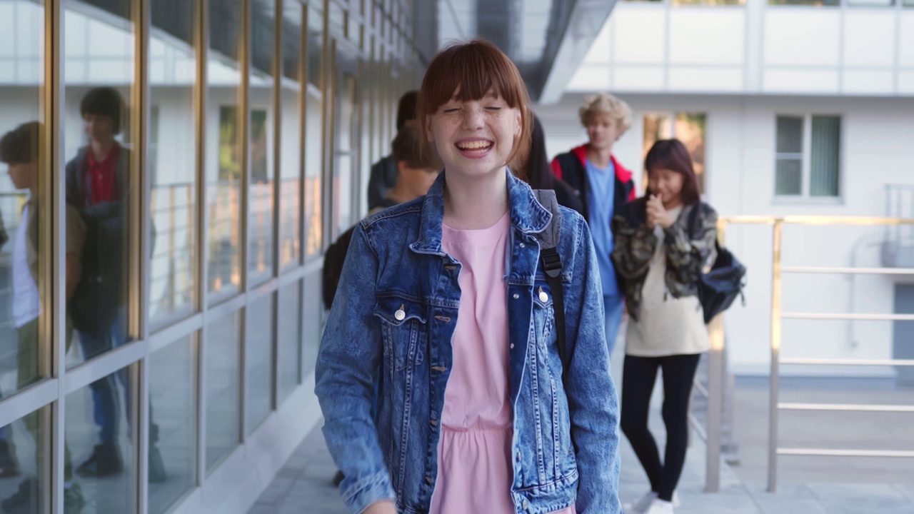 多莉推的照片，微笑的红发少女站在学校大楼外，看着镜头。视频下载