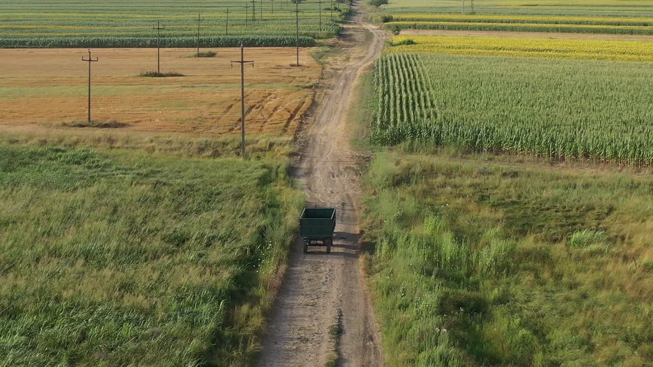 夏日午后，农用拖拉机拖着拖车沿着乡间土路行驶，无人机拍下的画面视频素材