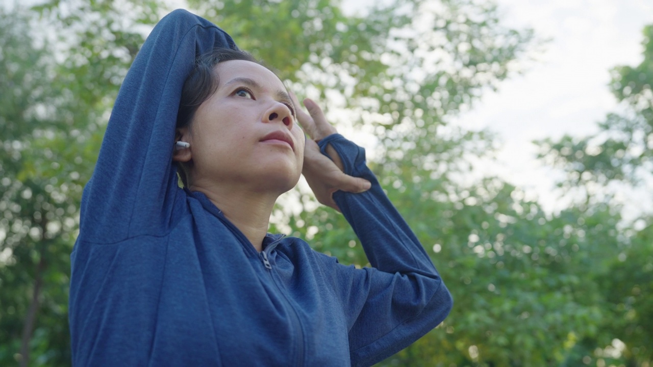 亚洲运动女性在户外跑步前热身，背景模糊公园视频下载