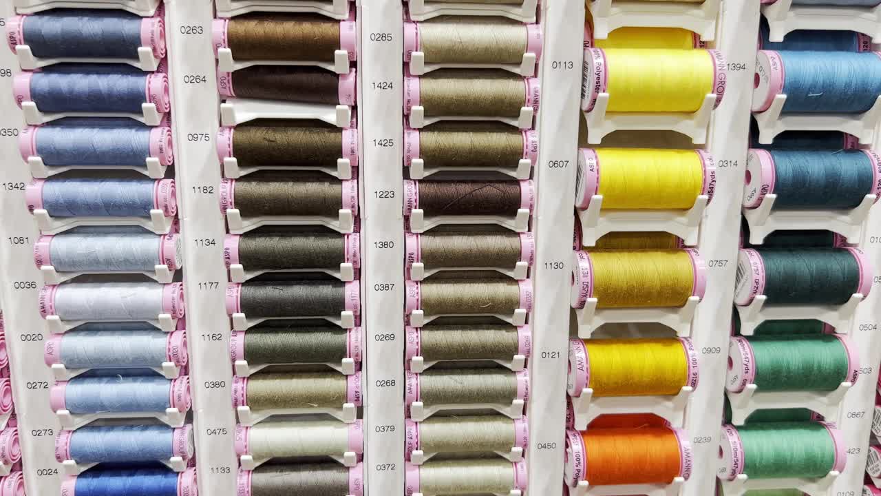 在一家服装工作室的车间里，许多不同颜色的线放在架子上。视频下载