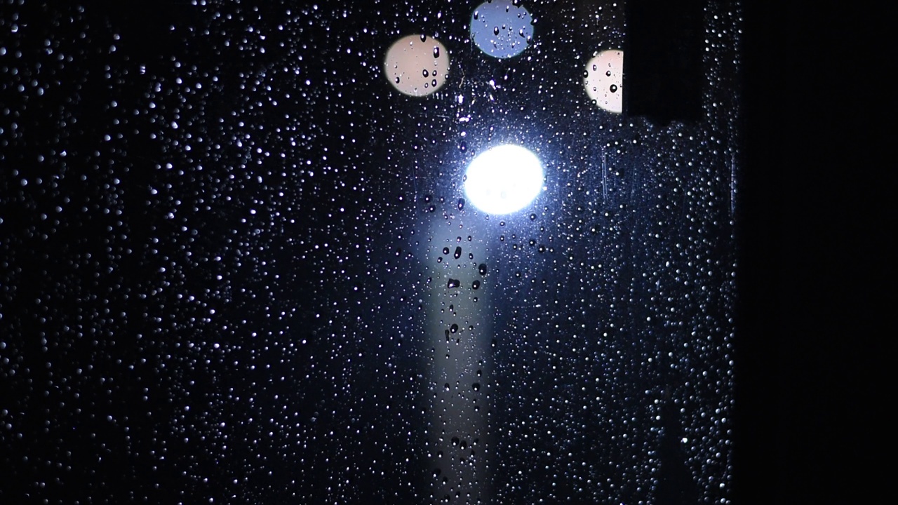 的夜晚。下雨了。雨滴落在玻璃和灯笼上。视频素材