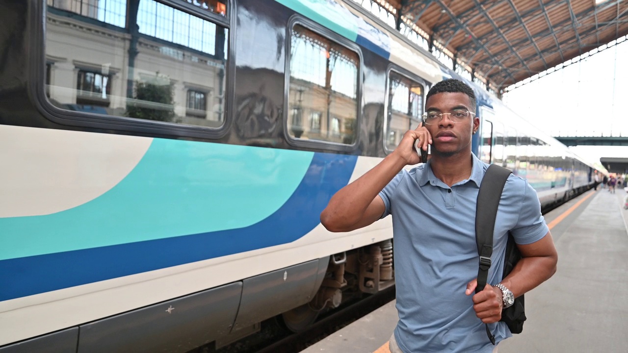 千禧一代有色人种上班时使用智能手机。一个商人在火车站打电话视频素材