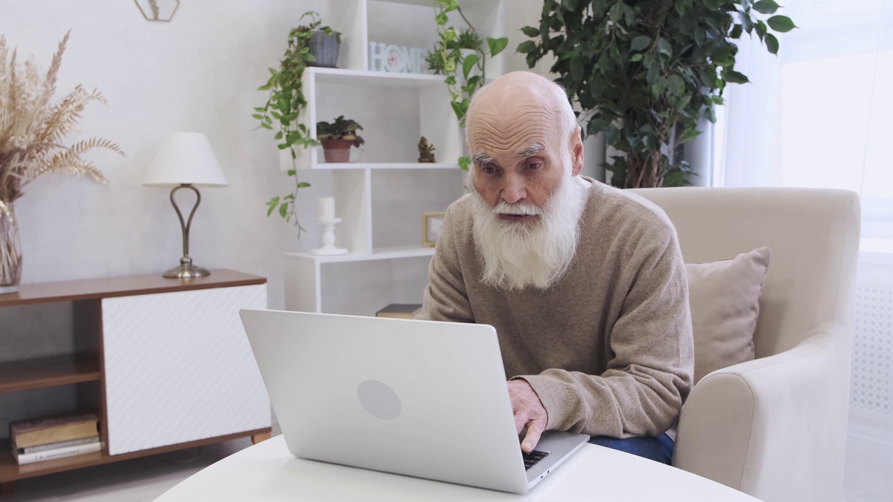 一位留着长白胡子的好奇老人正在使用笔记本电脑学习新技能视频下载