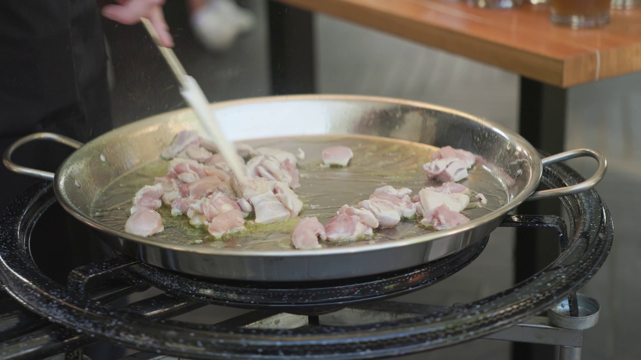 鸡柳片在煎锅里用油煎。用锅铲把炒好的肉翻炒一下。视频下载