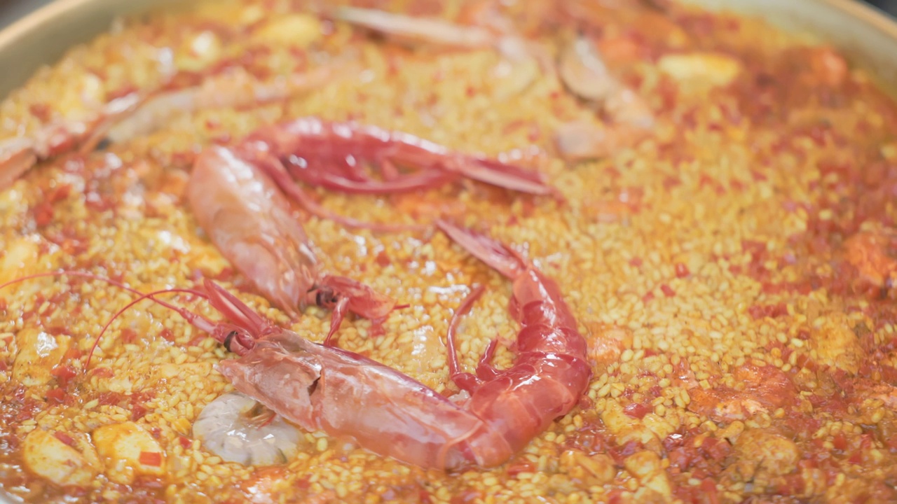 夏季露天食品市场，用虾、大米、香料、藏红花在巨大的海鲜饭锅里烹饪海鲜饭的过程:特写。西班牙菜，海鲜，美食视频下载