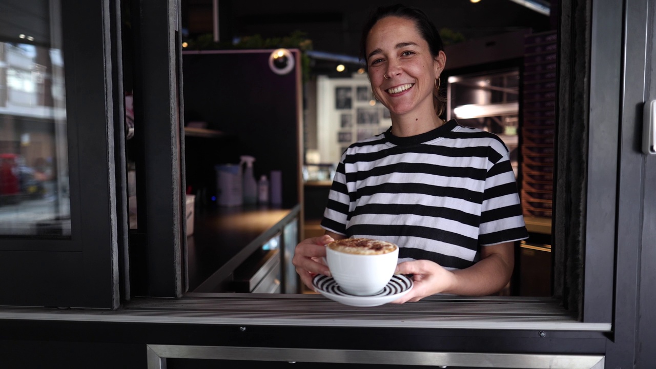 一个微笑的白人女服务员的肖像，拿着一个外卖咖啡杯，给外卖点餐视频素材