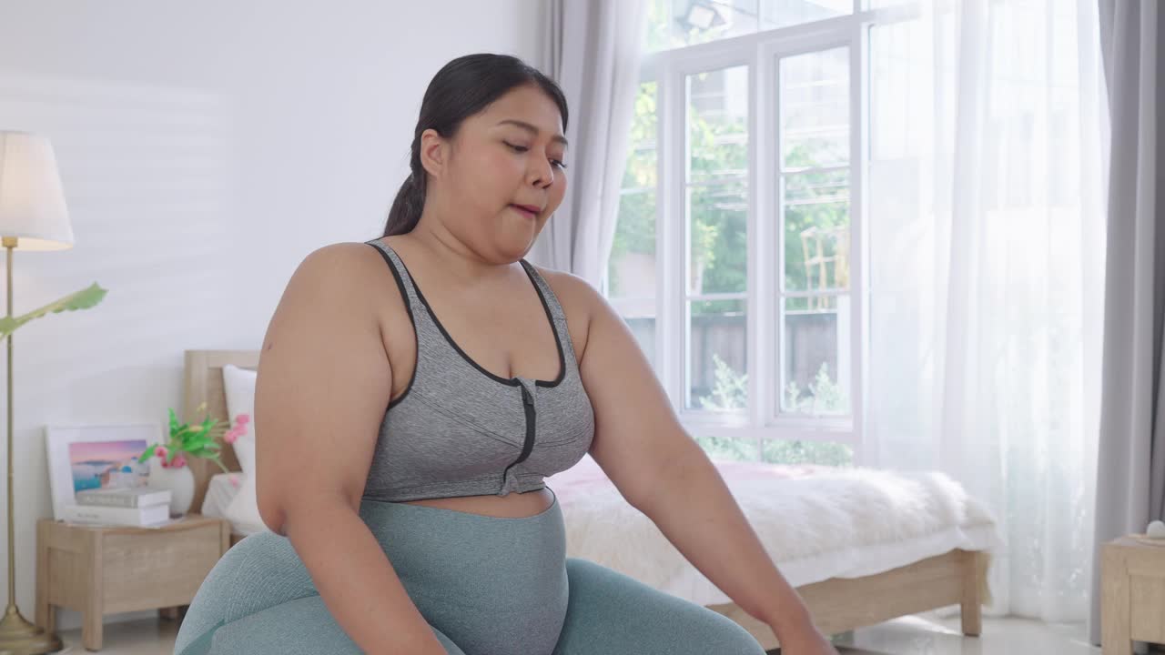 胖女人举哑铃在家锻炼视频素材