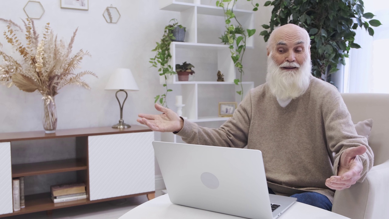 退休老人在家里用笔记本电脑和同事视频通话视频下载
