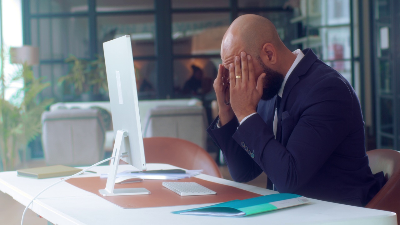 悲伤疲惫的工人在电脑上过度工作。不开心的失意商人。视频下载