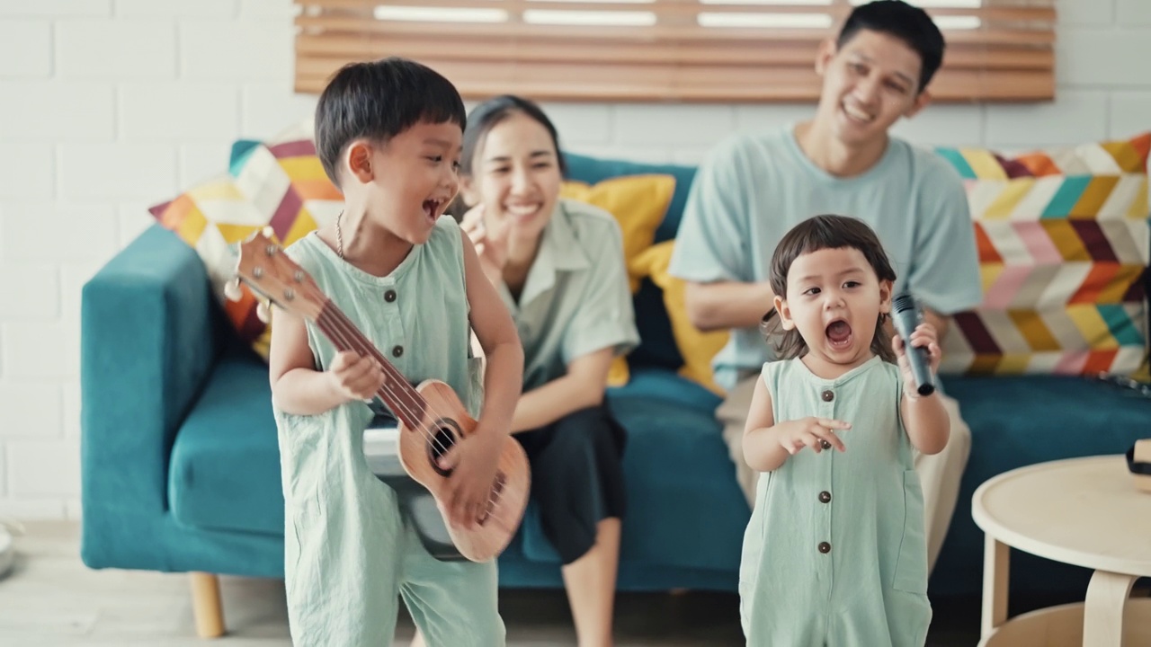 快乐的亚洲家庭在家里唱歌和弹吉他视频下载