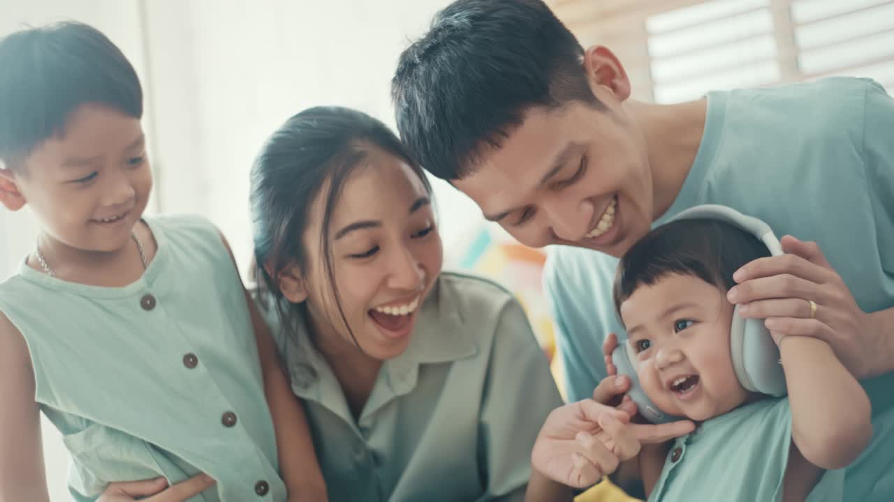 快乐的亚洲家庭在家里用耳机，慢动作视频素材