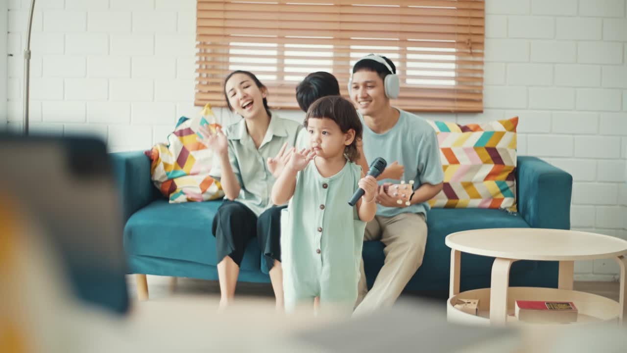 快乐的亚洲家庭在家里唱歌跳舞视频素材