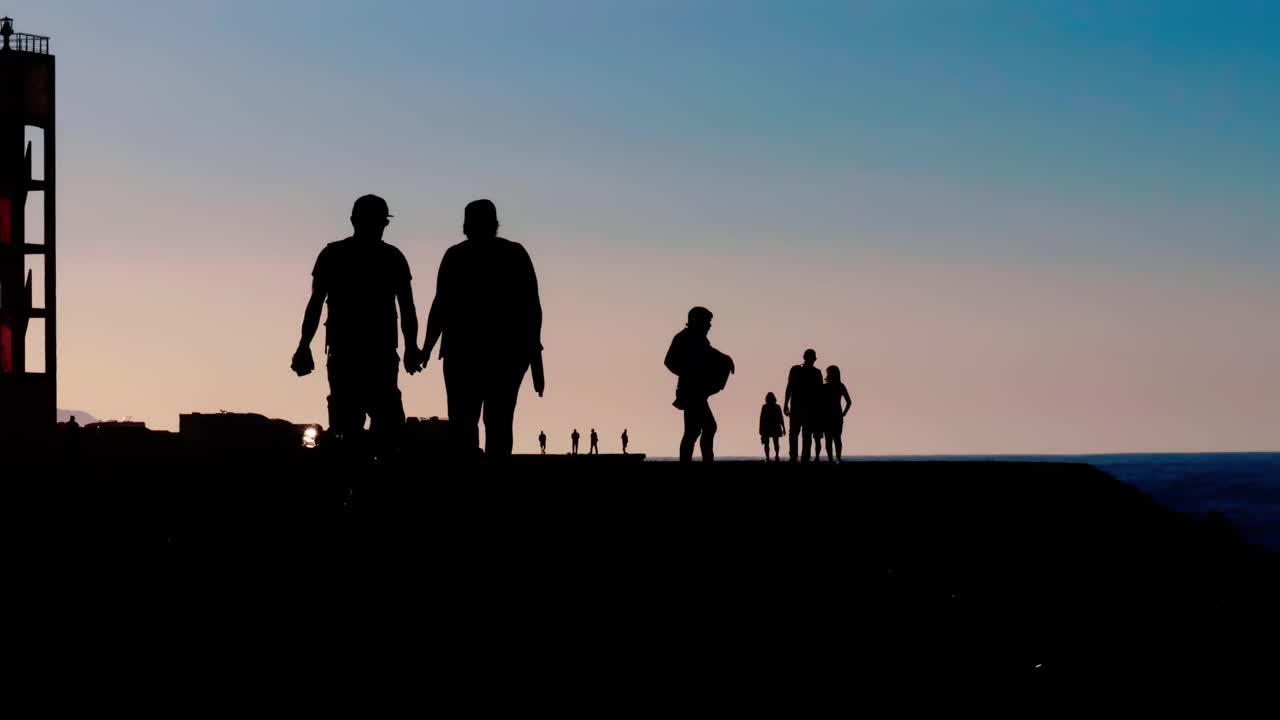 一对夫妇和其他人在日落时慢镜头在海边散步视频下载