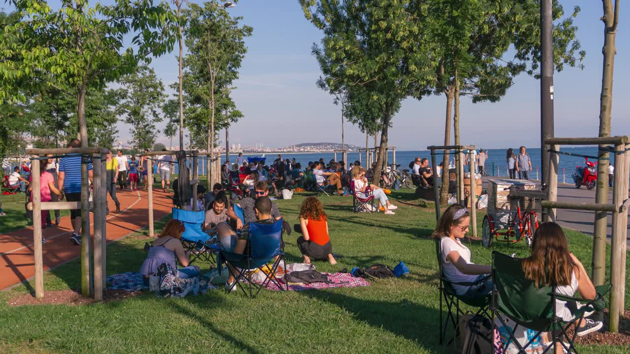 人们在海边的城市公园放松和散步的时间流逝。视频下载