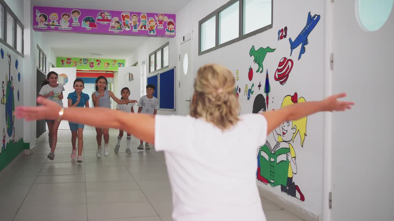 快乐的孩子们在学校走廊里奔向他们的老师视频下载