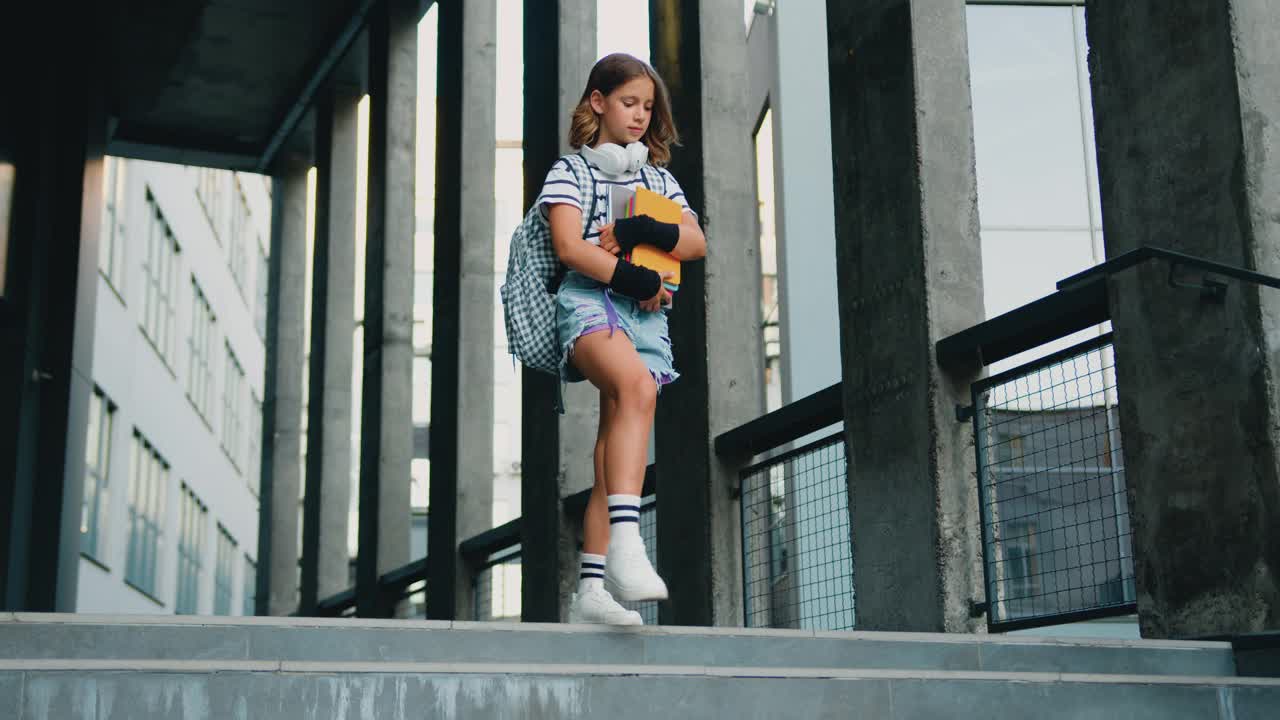 背着书包的快乐女孩放学后手里拿着书散步。学习冒险走知识的孩子小学生。主要的幼儿园。回到学校。视频下载