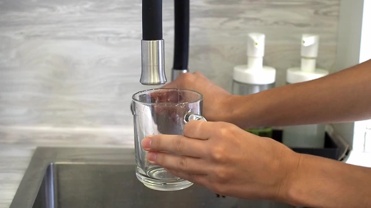 一个女人在厨房用空杯子倒自来水视频素材